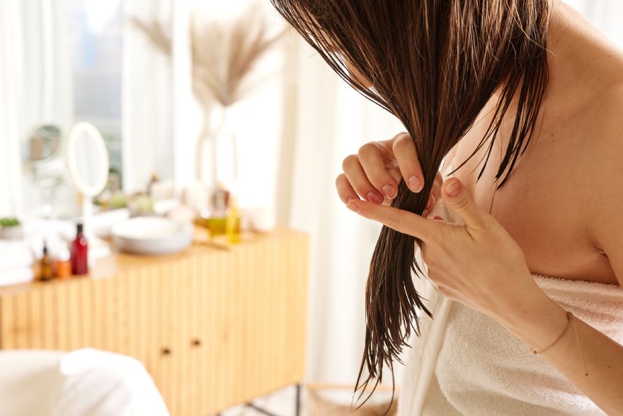 Žena neguje svoju kosu posle kupanja