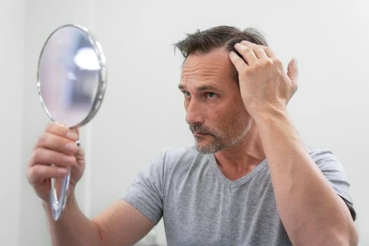 Muškarac gleda kosu u ogledalu.